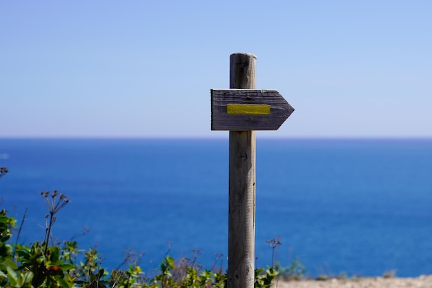 Zdjęcie drewniana żółta strzałka wskazująca kierunek ścieżki dla szlaku turystycznego na wybrzeżu morza oceanicznego spacer