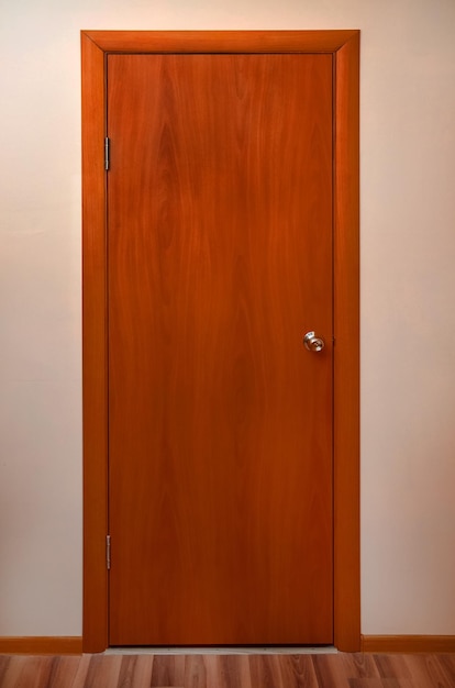 Drewniane drzwi z metalowym długopisem na pustej ścianie