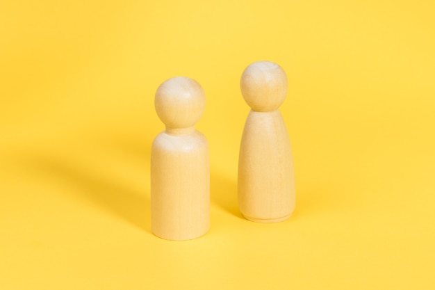 Drewniane figurki mężczyzny i kobiety na żółtym tle