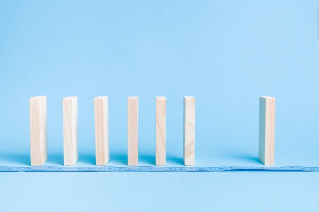 Drewniane kostki domino stoją w rzędzie na niebieskiej powierzchni