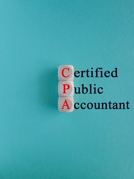 Drewniane kostki z czerwonymi słowami CPA skrót od certyfikowanego księgowego publicznego na jasnoniebieskim tle