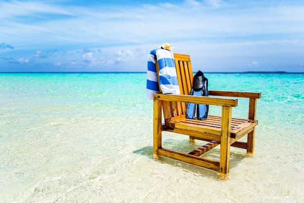 Drewniane krzesło stojące na Oceanie Indyjskim z muszlą na ręcznik i płetwami
