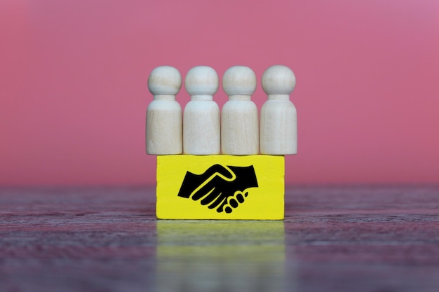 Zdjęcie drewniane lalki i drewniany sześcian z ikoną uścisku dłoni umowa biznesowa koncepcja przejęcia fuzji