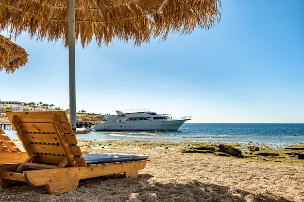 Drewniane leżaki pod parasolem słomkowym na plaży