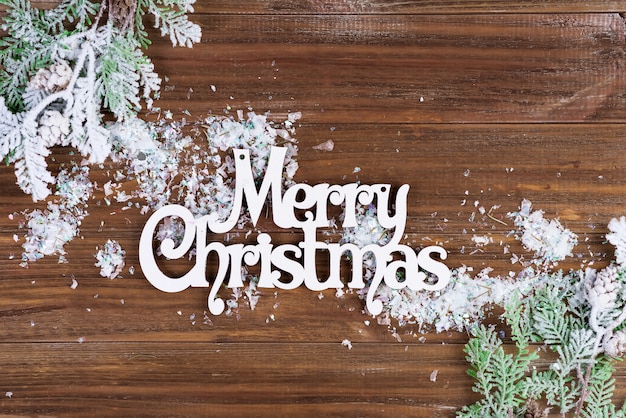 Zdjęcie drewniane litery wesołych świąt z dopasowanie gałęzi i śniegu na drewniane tła. kartka świąteczna. leżał płasko