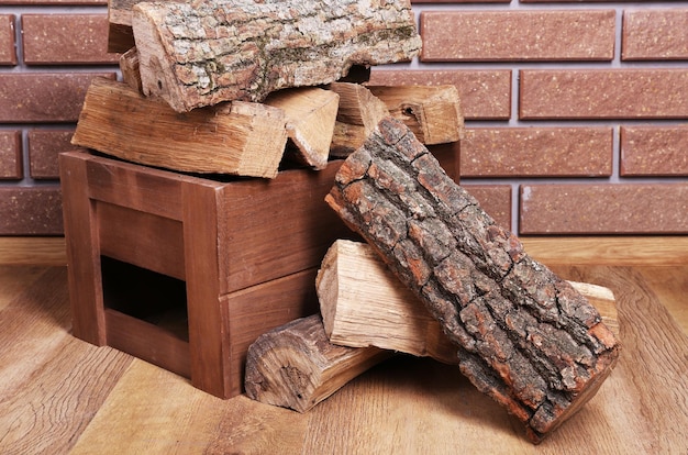 Zdjęcie drewniane pudełko z drewna opałowego na podłodze na tle cegły