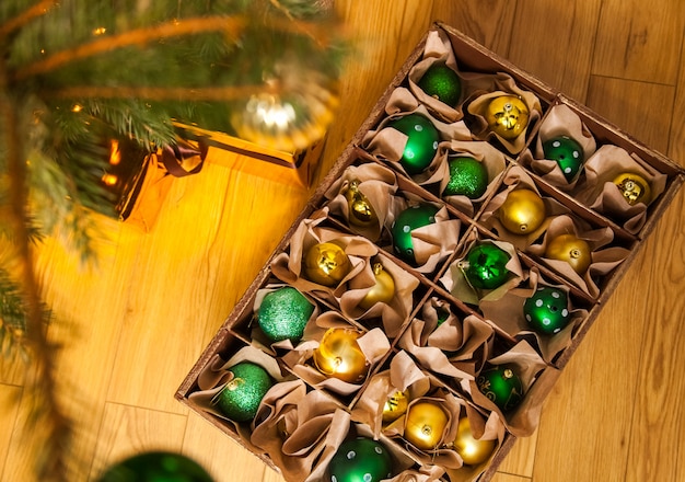 Drewniane pudełko ze złotymi i zielonymi kulkami i zabawkami do dekoracji, świąt Bożego Narodzenia i Nowego Roku
