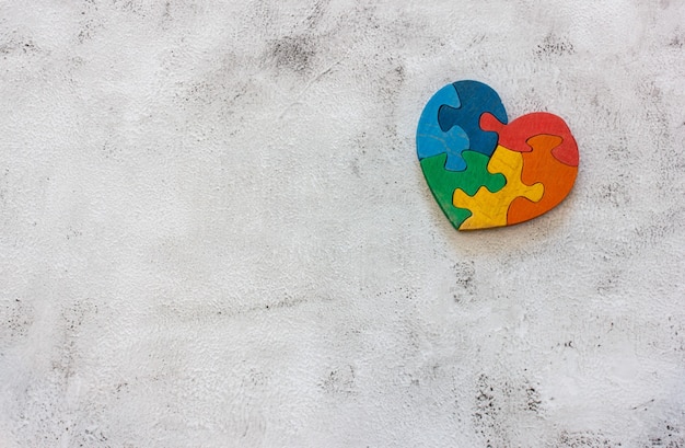 Drewniane puzzle wielokolorowe w kształcie serca na szarym tle. Koncepcja Walentynki, związek. Miejsce na tekst