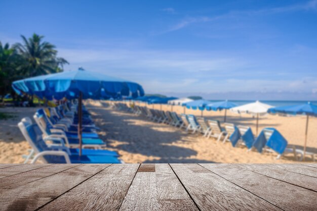 Drewniany blat na niewyraźne parasol i osób relaks na białej, piaszczystej plaży