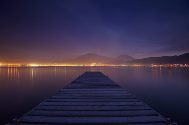 Drewniany jetty na dennym zmierzchu i nieba odbicia wodzie. Długi czas ekspozycji.