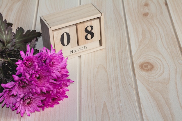 Zdjęcie drewniany kalendarz 8 marca obok fioletowych kwiatów na drewnianym stole selektywne skupienie szczęśliwy dzień kobiety