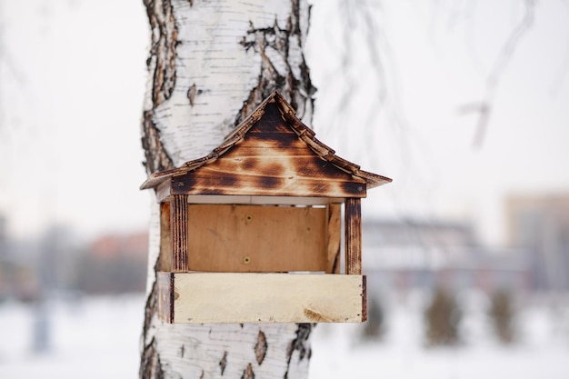 Drewniany karmnik dla ptaków. Karmnik dla ptaków pokryty śniegiem w okresie zimowym, pomagający ptakom zimą.