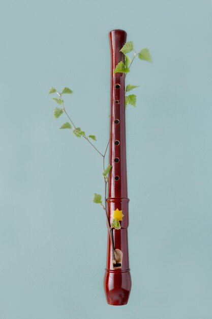 Zdjęcie drewniany klocek flet owinięty gałązką z liśćmi na niebieskim tle