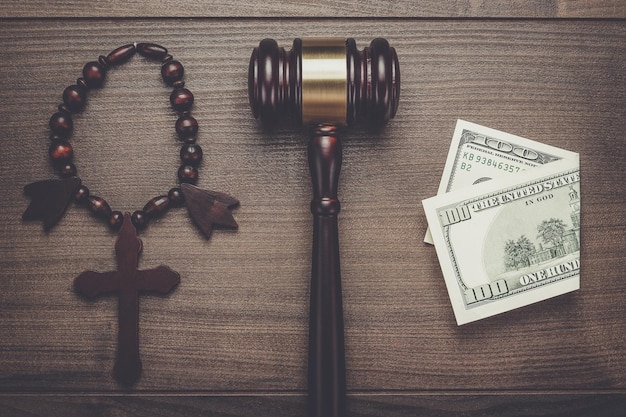 Zdjęcie drewniany krzyż młotek i pieniądze na brązowym tle stołu