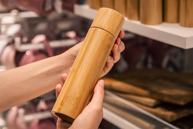 Drewniany młynek do soli lub pieprzu w kobiecych rękach w supermarkecie