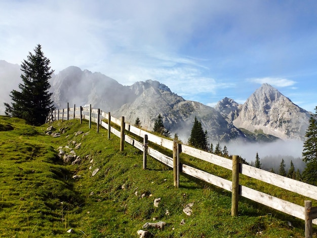 Drewniany płot wsi w perspektywie na zboczu górskim Góry Skaliste i chmury w tle