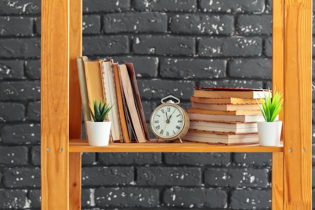 Drewniany regał z książkami i innymi rzeczami na czarnym murem