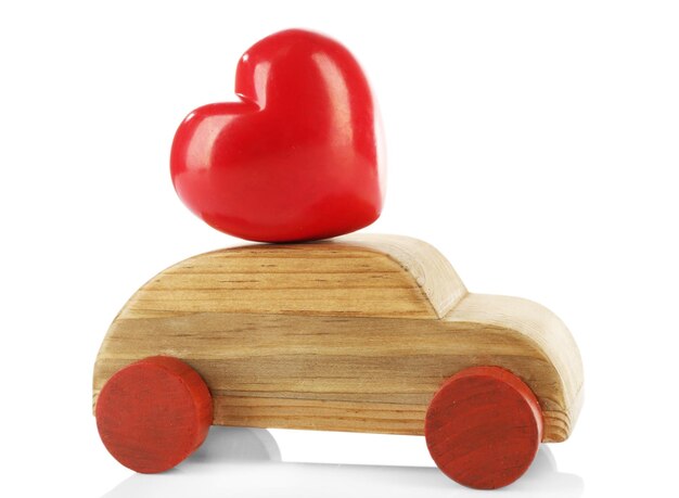 Drewniany samochód z małym czerwonym sercem na białym tle