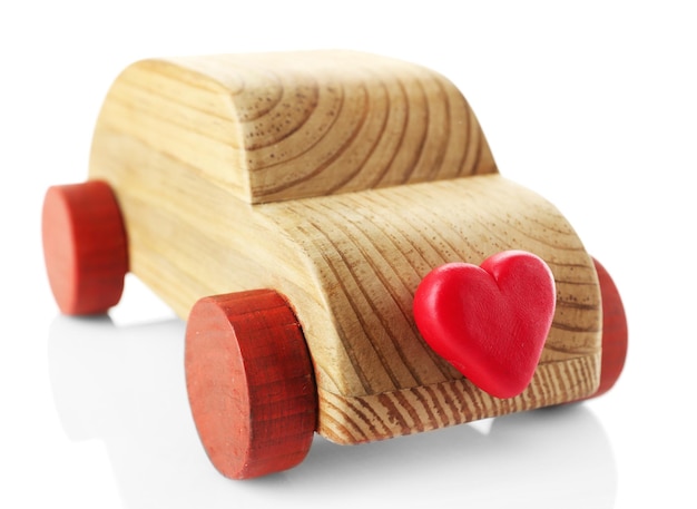 Drewniany samochód z małym czerwonym sercem na białym tle