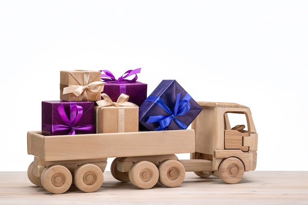 Zdjęcie drewniany samochodzik. ciężarówka z prezentami w kolorowych pudełkach.