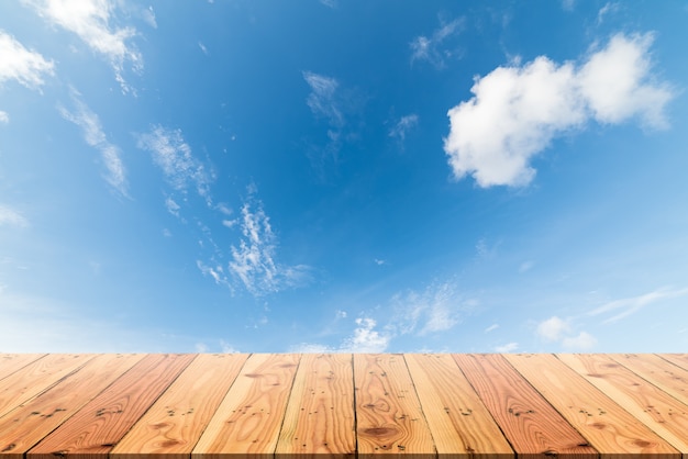 Drewniany stół na niebieskim niebie i bielu obłocznym tle.