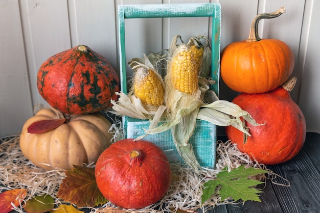 Drewniany stół ozdobiony warzywami, dyniami, kukurydzą i jesiennymi liśćmi. Jesienne tło. Koncepcja Święto Dziękczynienia lub Halloween.