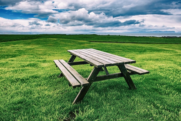 Drewniany stół piknikowy w Islandii na zielonej łące Podróżuj na zewnątrz latem w tle