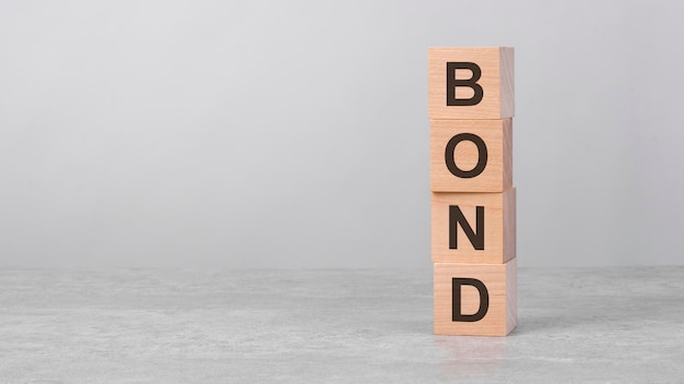 Drewniany sześcian na białym stole z koncepcją obligacji tekstowych biznesu inwestycji finansowych gospodarki kopia miejsca po lewej stronie, aby zaprojektować szare tło