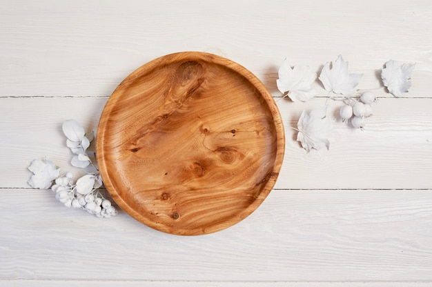 Zdjęcie drewniany talerz z białymi jagodami i liśćmi na drewnianym stole