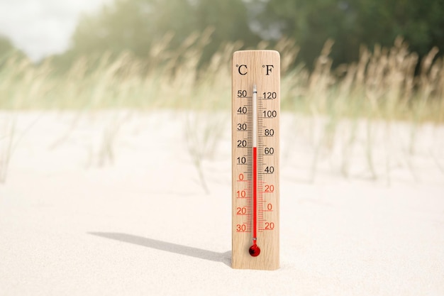 Drewniany termometr w skali Celsjusza i Fahrenheita w piasku Temperatura otoczenia plus 20 stopni