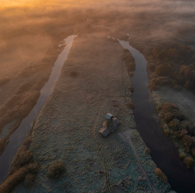 Drewniany wiatrak na wsi o świcie i mgła jesienią, rano pierwsze przymrozki. górny widok z lotu ptaka z drona