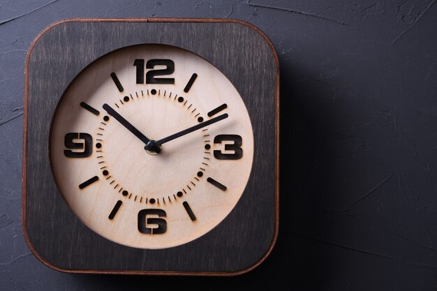 Zdjęcie drewniany zegar wykonany w ręku na drewnianym stole. zbliżenie.