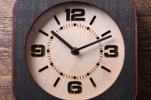 Drewniany zegar wykonany w ręku na drewnianym stole. Zbliżenie.