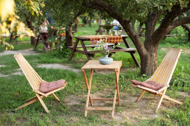 Drewniany zestaw mebli ogrodowych na piknik z krzesłami i stołem w letnim sadzie.