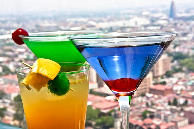drinki koktajlowe Martini blue curacao i Martini green midori przyozdobione sokiem wiśniowo-pomarańczowym