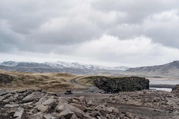 Droga ciągnąca się aż po horyzont, pokryte śniegiem skaliste góry. W pobliżu Black Beach Vik, Islandia