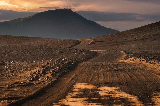 Droga gruntowa i góra wulkaniczna do Landmannalaugar wśród odległej dziczy wieczorem na islandzkich wyżynach