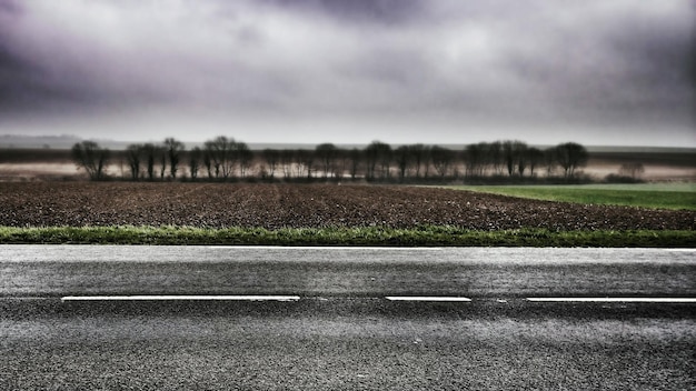 Zdjęcie droga przechodząca przez pole na chmurowym niebie