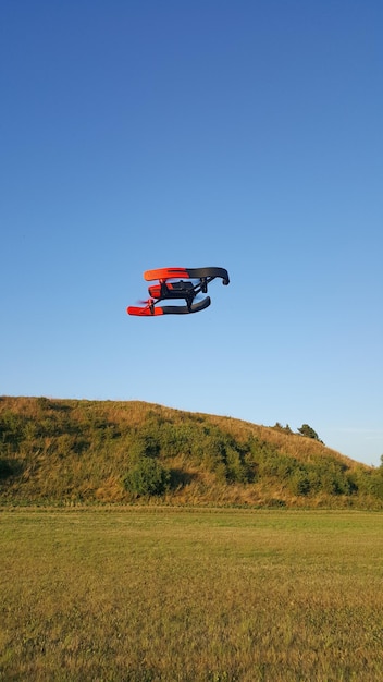 Zdjęcie dron latający nad krajobrazem na czystym niebieskim niebie