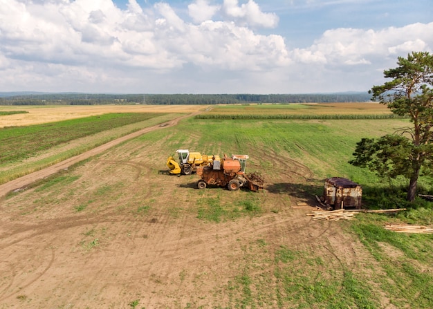 Dron Nad Wiejskimi Kombajnami Stoi Na Szerokim Polu Z Lotu Ptaka. Krajobraz Rolnictwa.