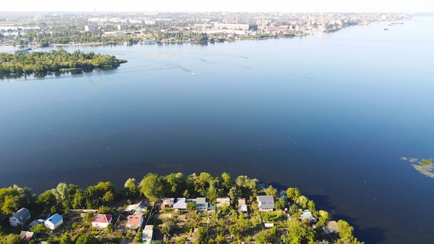 Dron przelatuje nad falującą rzeką koloru niebieskiego otoczoną lokalną wioską