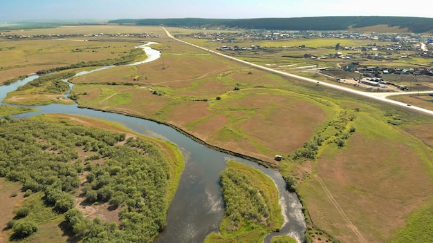 Dron Przelatuje Nad Rzeką Krzywą Otoczoną Lasami I Polami Z Drogą Gruntową, Krajobraz Z Lotu Ptaka