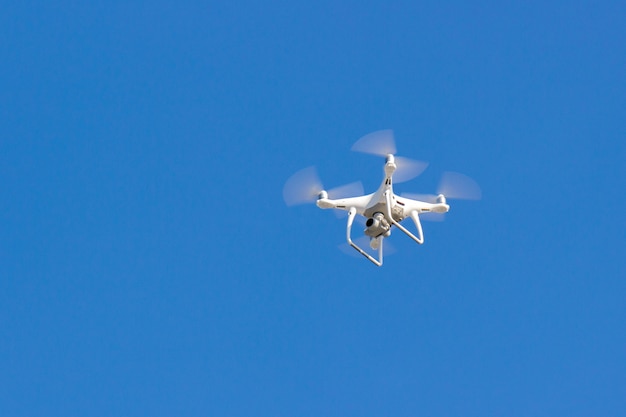 Dron Quadkoptera Leci Na Niebieskim Niebie. Bezzałogowy Statek Powietrzny. Zdalne Nagrywanie Wideo Z Wysokości. Nowoczesny Aparat Cyfrowy