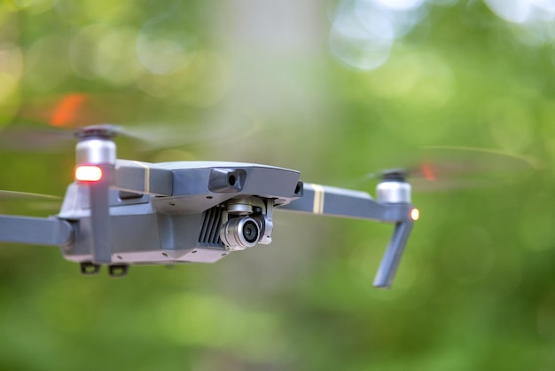 Dron z rozmazanymi szybko obracającymi się śmigłami i kamerą wideo lecący w powietrzu