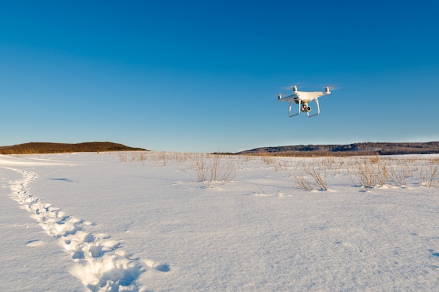Drone lecący nad polem pokryte śniegiem w słoneczny zimowy dzień