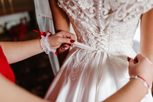 Druhna pomaga narzeczonej zapiąć gorset i dostać sukienkę, przygotowując rano pannę młodą na dzień ślubu.
