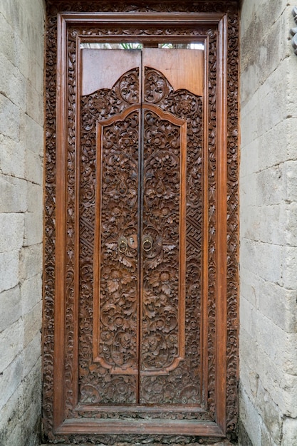 Drzwi rzeźbione w drewnie balijskim z tradycyjnymi lokalnymi ornamentami. Lokalne tradycje i koncepcja rzemiosła