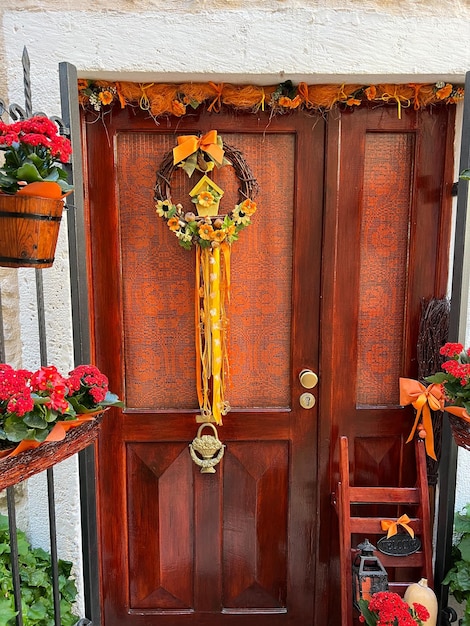Drzwi wejściowe z ozdobnym wieńcem i kwiatami doniczkowymi na ścianie