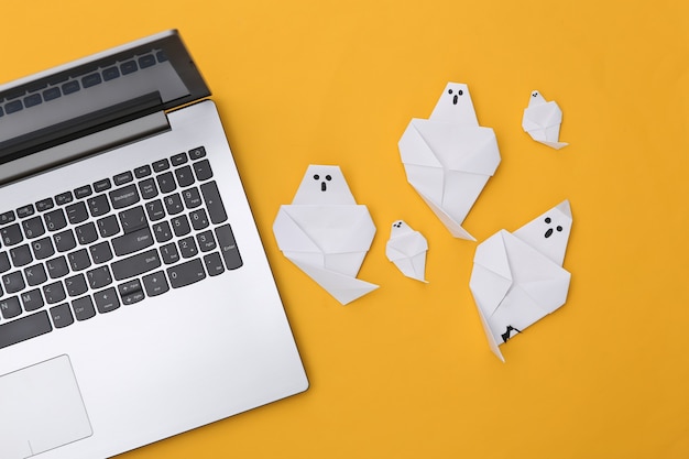 Duchy laptopa i origami na żółtym tle. Motyw Halloween. Widok z góry