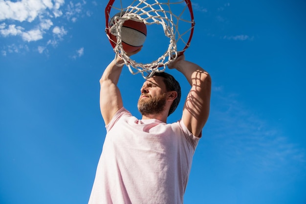 Dunk w koszu Slam Dunk w ruchu słoneczny lato aktywność mężczyzna z piłką do koszykówki na korcie zawodowy koszykarz szkolący się na świeżym powietrzu facet ma sportową motywację sport i hobby